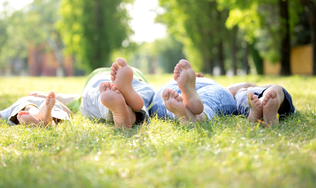 Earthing - family lying on the grass with bare feet